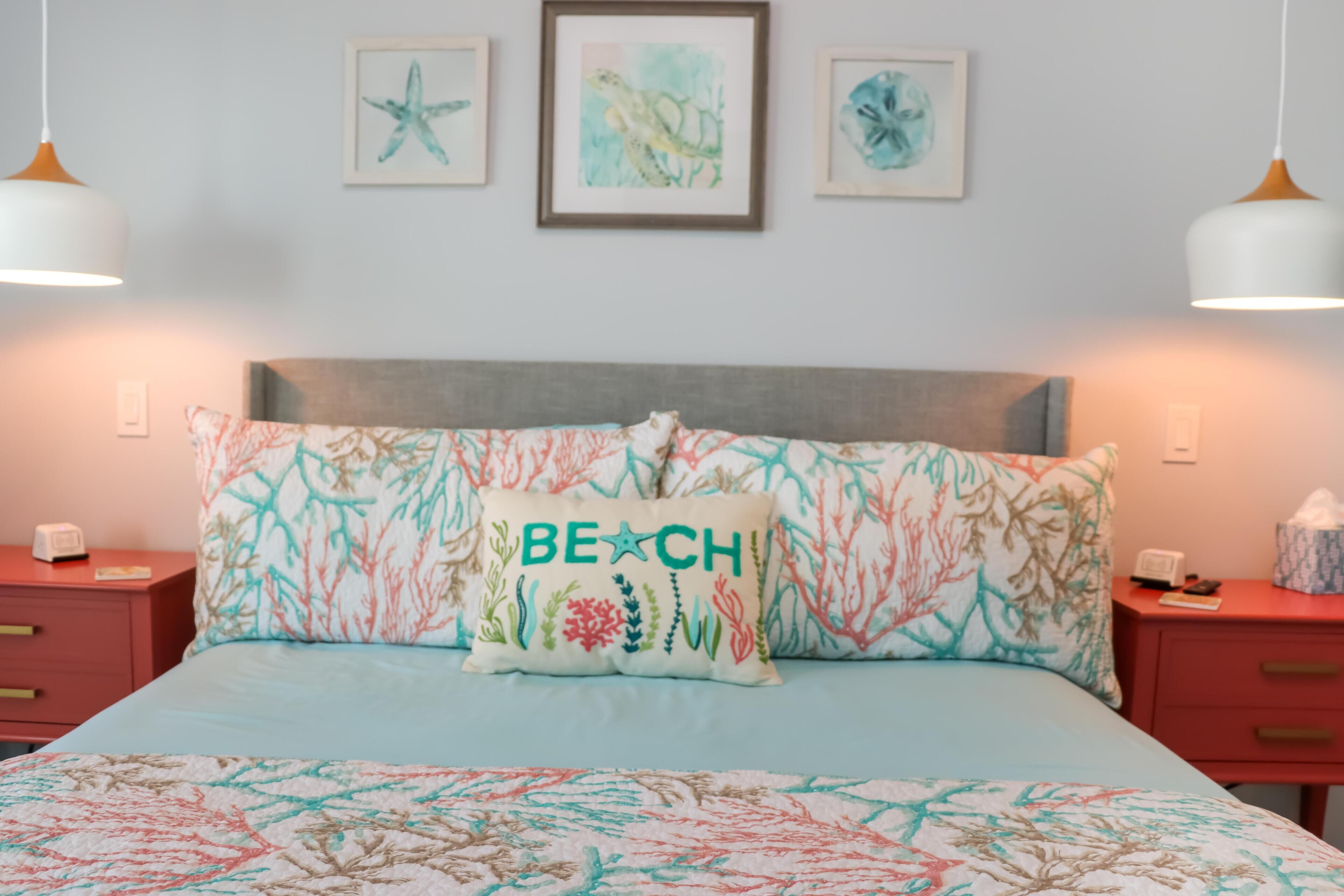 A bedroom with a bed, two nightstands, and wall art.