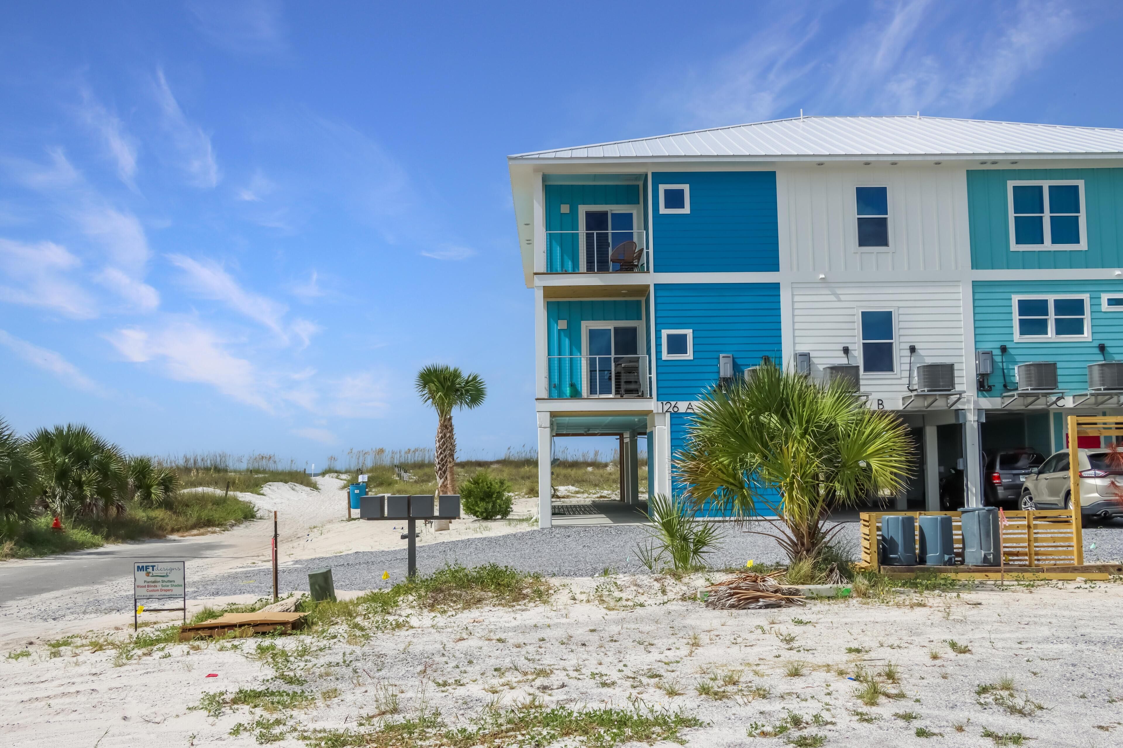 A two-story building with a blue and white exterior, a covered outdoor area, and a parking lot with a few cars.