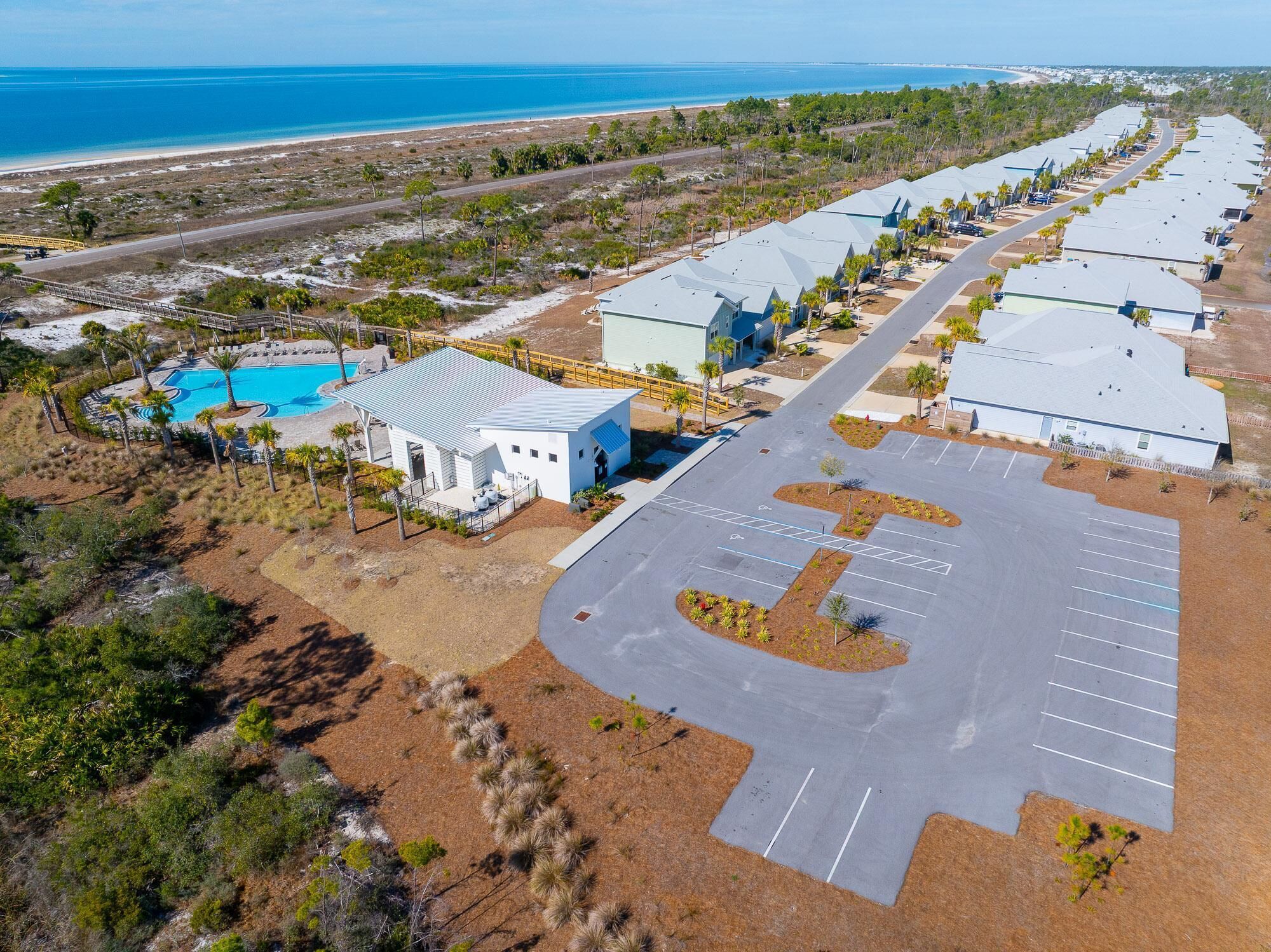 An aerial view of a resort with multiple buildings, a swimming pool, and a parking lot.