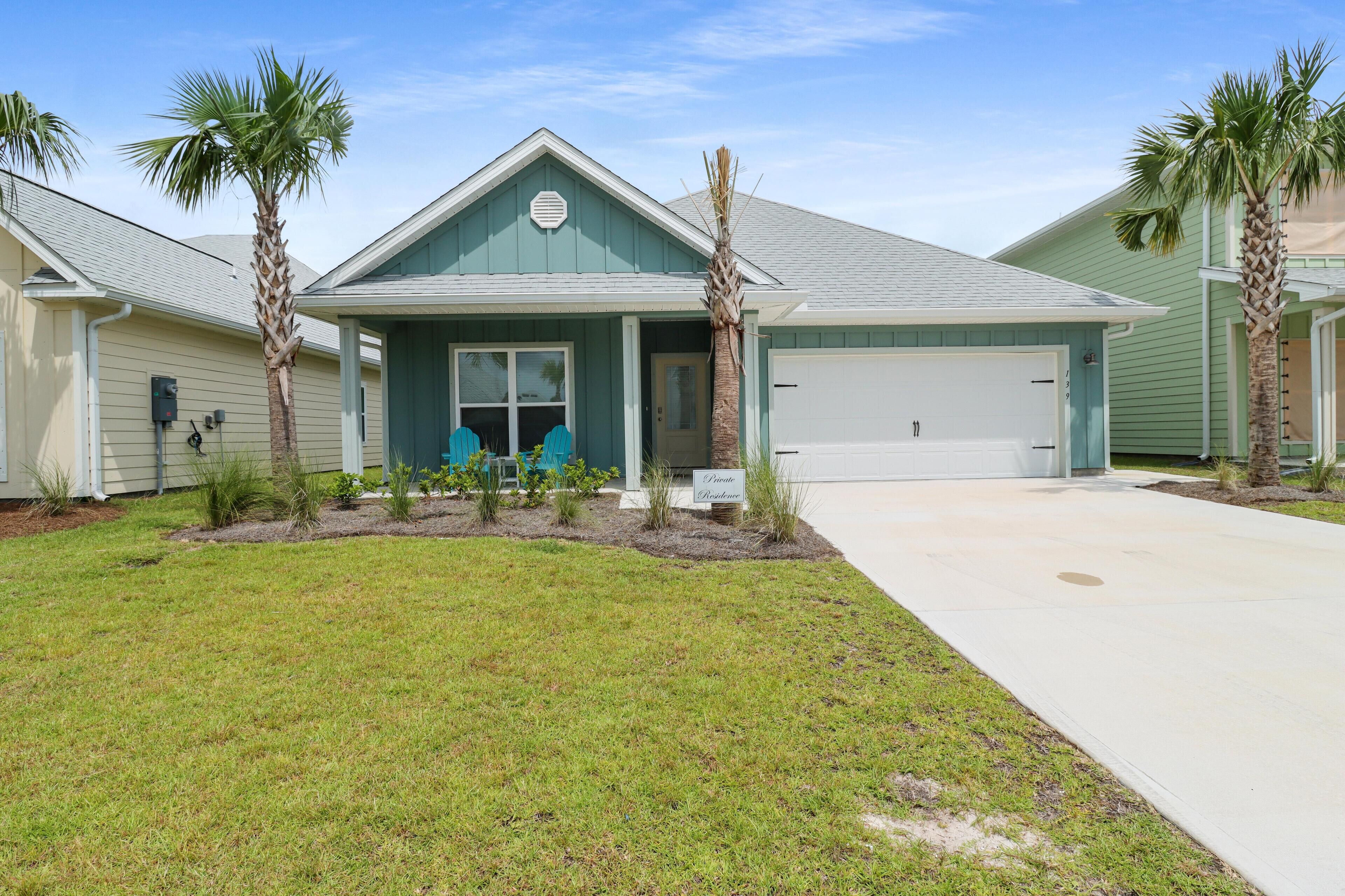 A single-story house with a garage, a front lawn, and palm trees.