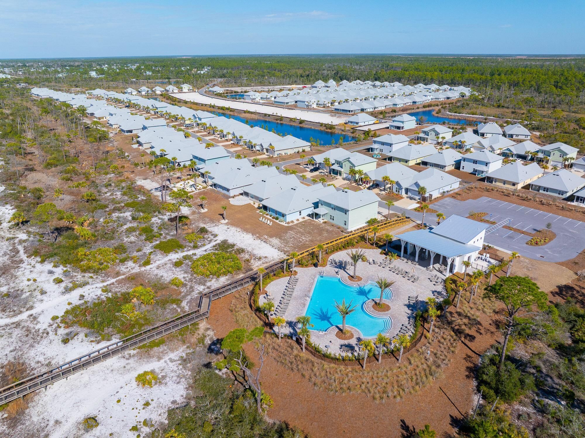 An aerial view of a resort with multiple buildings, a central pool area, and surrounding natural landscape.