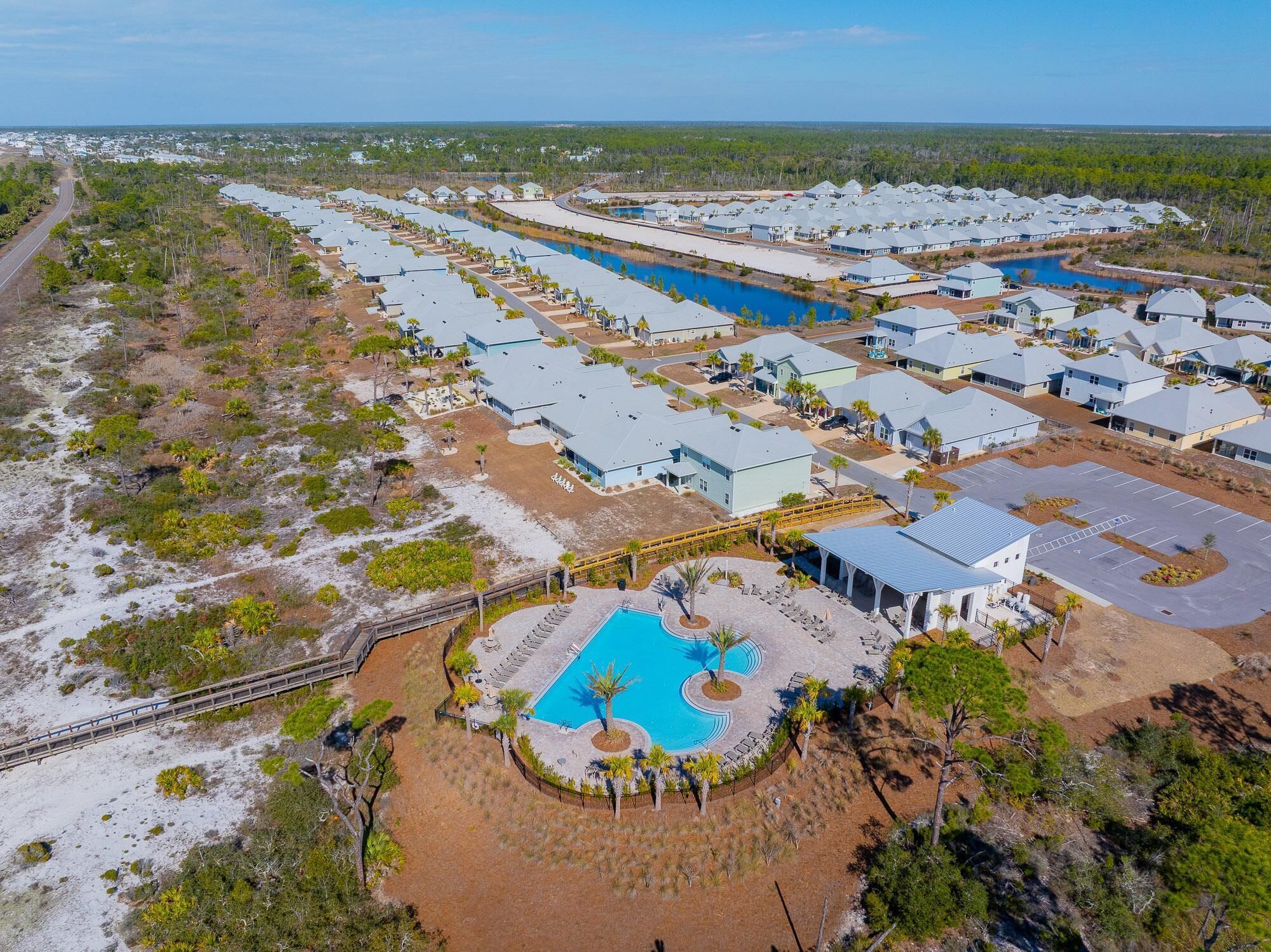 A resort with multiple buildings, a central pool, and a beach area.