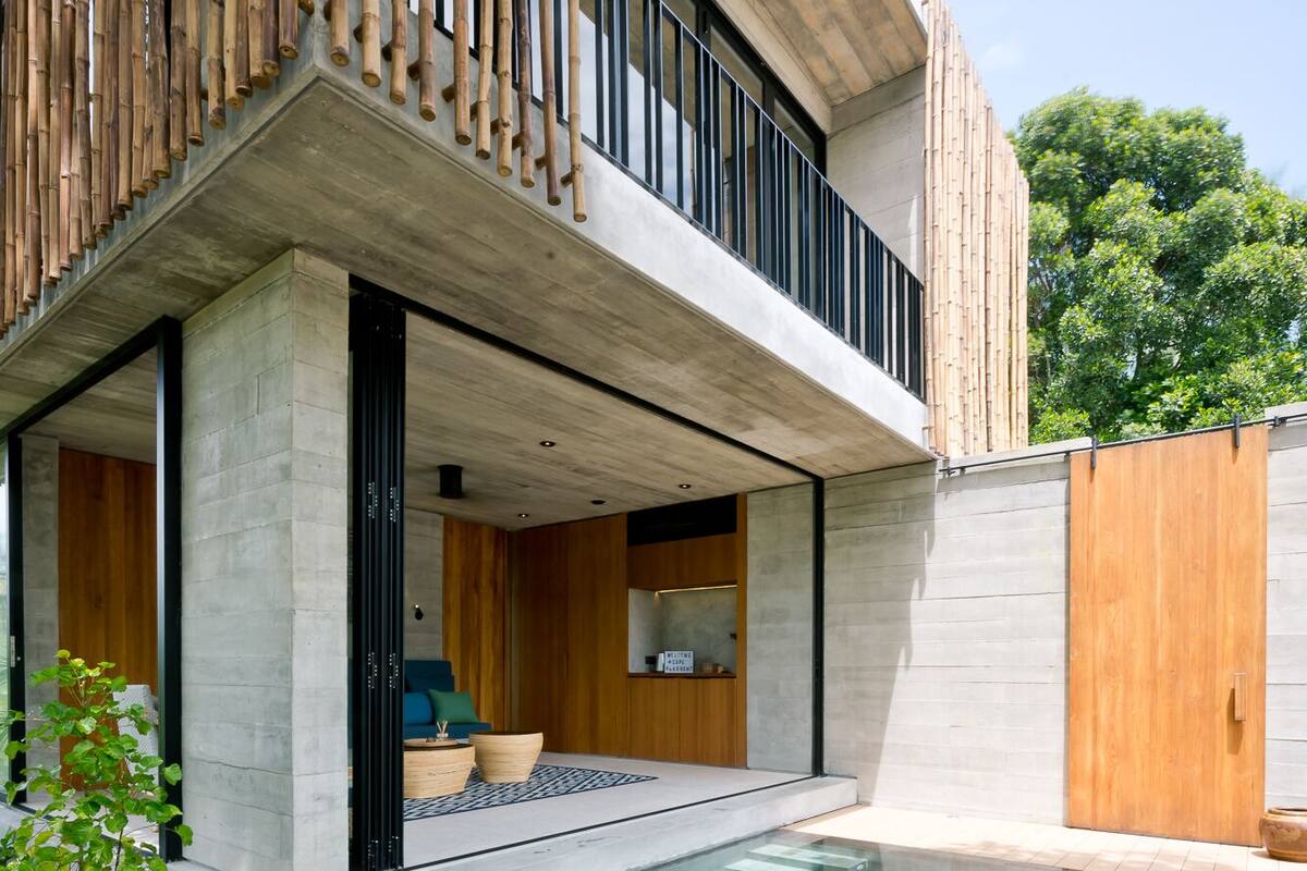 Una casa moderna con piscina, balcón y valla de madera.