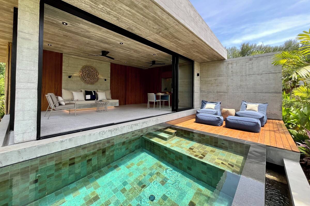 Un espacio al aire libre moderno con piscina, asientos y vistas hacia el interior.