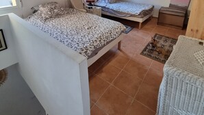 Una camera da letto con due letti, soffitto in legno, una finestra e un piccolo tavolo.