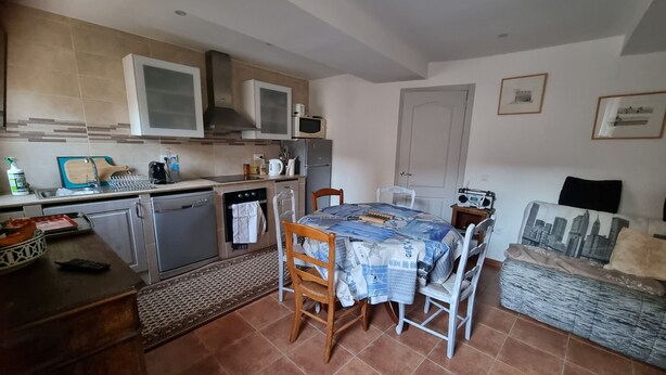 Una cucina con tavolo e sedie, forno a microonde, piano cottura e lavello.