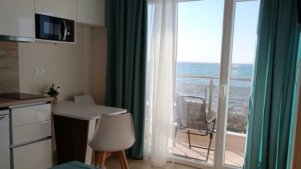 Habitación de hotel con cama, escritorio, silla, balcón y vista al mar, además de un microondas.