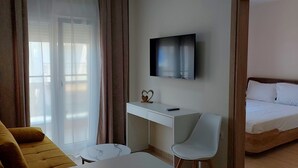 Una habitación de hotel con una cama, un escritorio, un televisor, un sofá y una mesita.