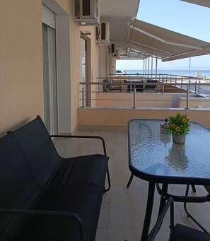 A balcony with a sofa, a table, and a vase with sunflowers. - Navarino Luxe Suites with Sea View (Thermaikos)