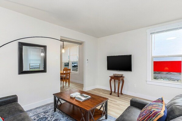 A modern living room with a flat-screen TV, a wooden coffee table, and a gray sofa.