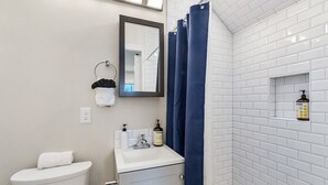 Une salle de bain équipée de toilettes, d’un lavabo, d’un miroir et d’un rideau de douche.