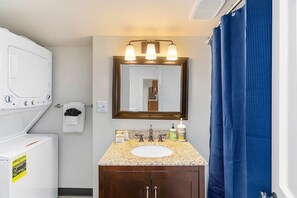 A bathroom with a white sink, a mirror, and a shower curtain. - The Night Owl Perch in Stanwood (Stanwood)