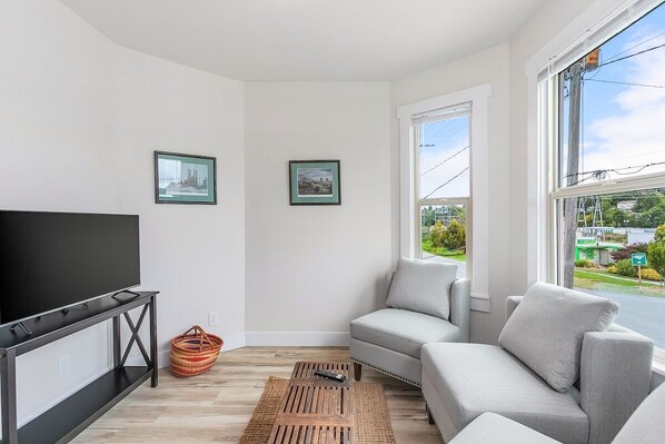 A modern living room with a flat-screen TV, a grey sofa, and two framed pictures on the wall. - The Night Owl Perch in Stanwood (Stanwood)