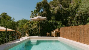 A swimming pool with a wooden deck, a wicker chair, and a small table. - Holiday Home 'Casa Familia' with Private Pool, Wi-Fi and Air Conditioning (Sa Pobla)