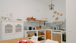 A modern kitchen with white cabinetry, a wooden dining table, and a fruit bowl. - Holiday Home 'Casa Familia' with Private Pool, Wi-Fi and Air Conditioning (Sa Pobla)