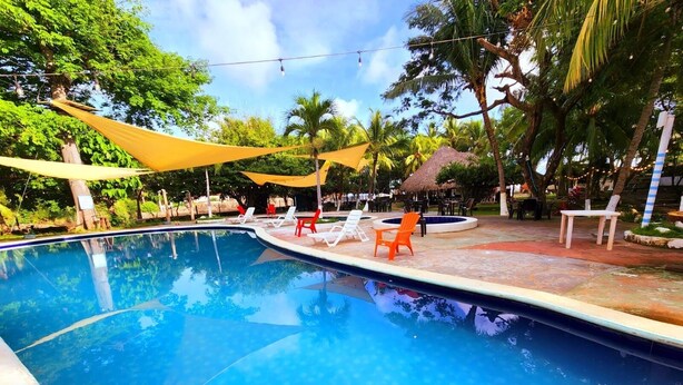 A swimming pool with lounge chairs and a shaded area. - Playa Linda Surf Hotel (Tamanique)