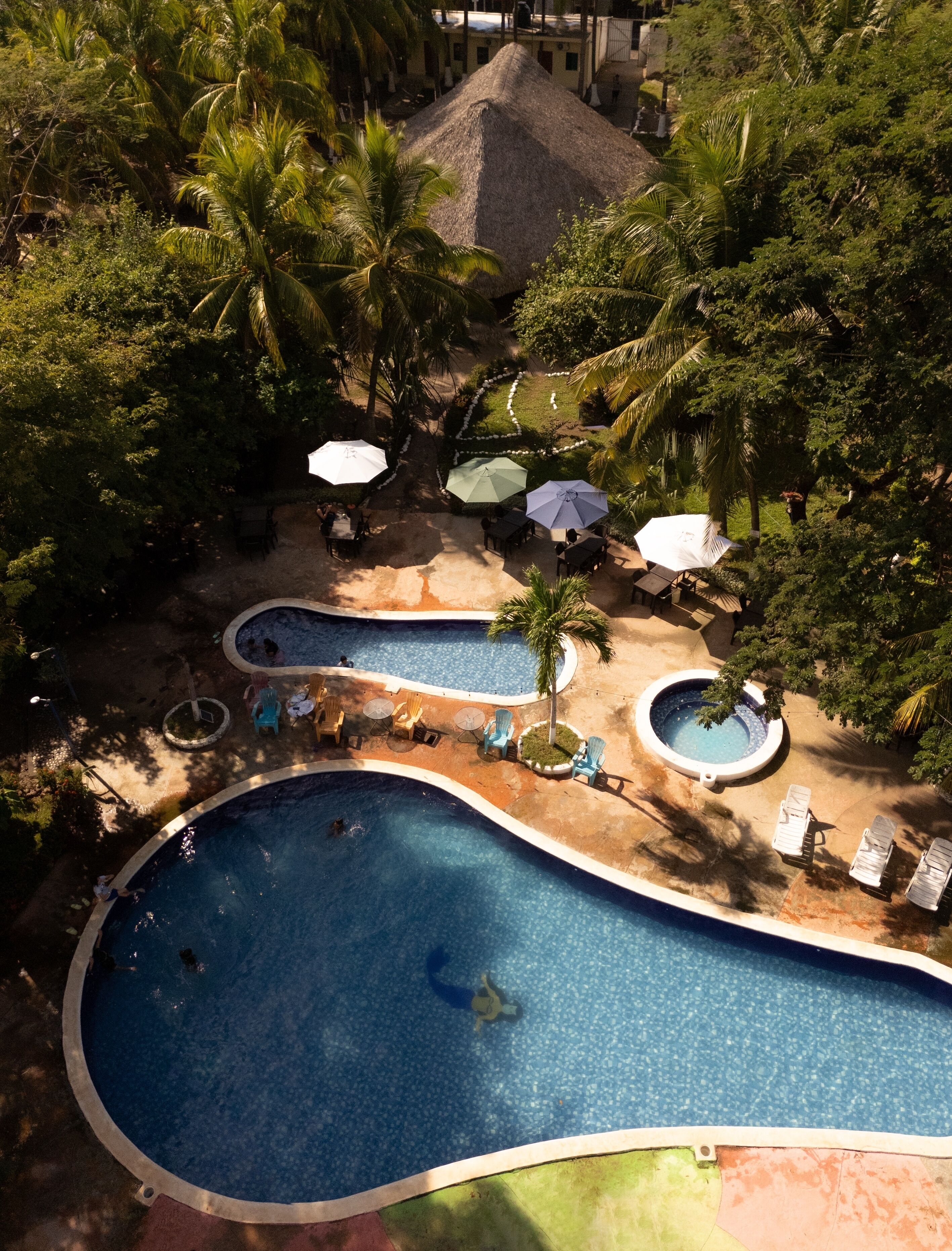 Een resort met meerdere zwembaden, ligbedden en parasols.