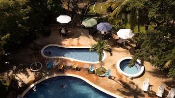 Een resort met meerdere zwembaden, ligbedden en parasols.