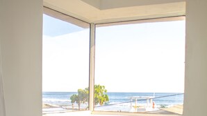 A room with a large window offering a view of the beach and ocean. - Playa Linda Surf Hotel (Tamanique)