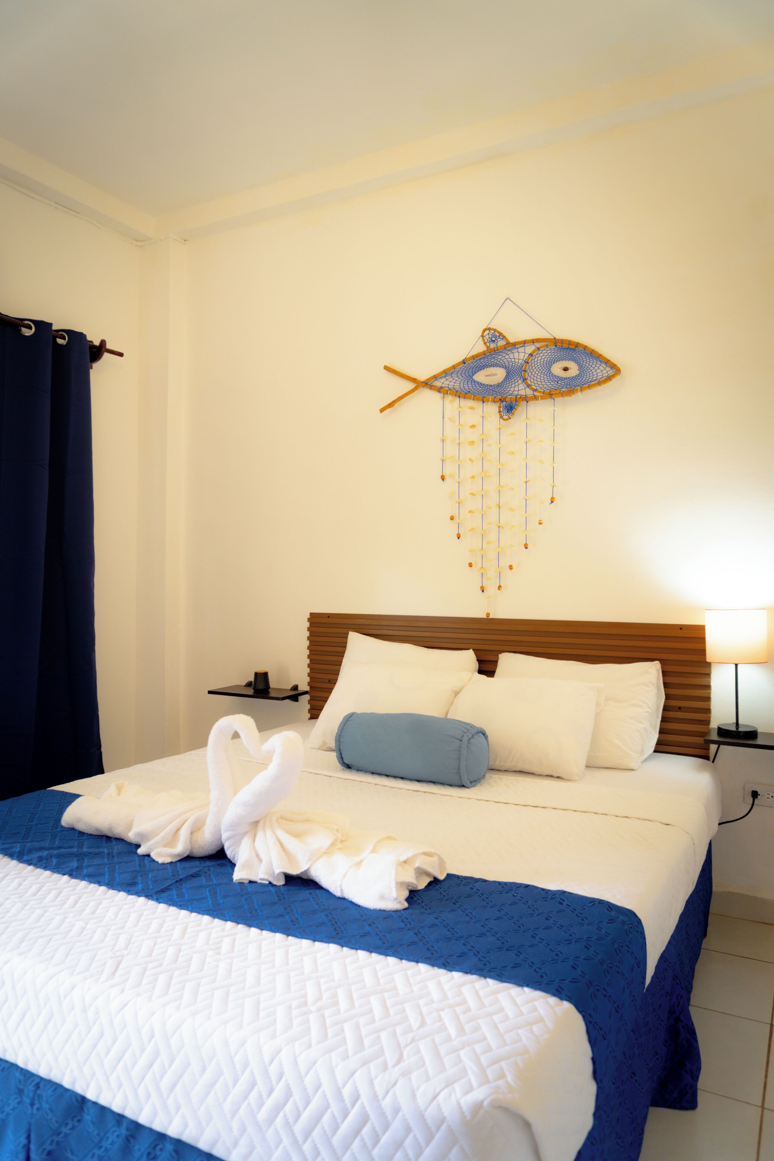 Ein Hotelzimmer mit einem Bett, einer Wanddekoration mit Fischen und einem Nachttisch mit Lampe.