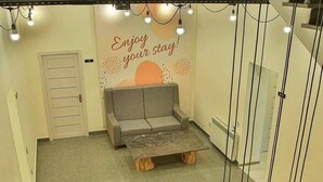 A hotel lobby with a grey sofa, a wooden coffee table, and a staircase with metal railings. - Central Hostel (Sheki)