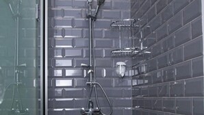 A modern bathroom with a glass shower enclosure, a handheld showerhead, a wall-mounted faucet, and a chrome shower tray. - Central Hostel (Sheki)