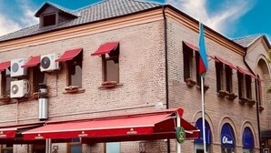 A building with a red awning labeled "CAFE CENTRAL" and a sign for "HOTEL." - Central Hostel (Sheki)