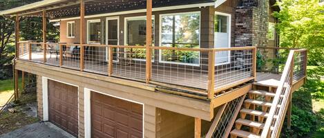 A two-story wooden deck with a covered area, a garage, and a staircase leading to the upper level.