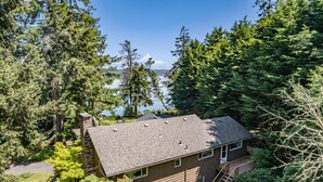 Une maison avec un toit en pente, une terrasse et une vue sur un lac.
