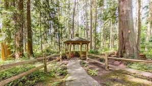 A stone pathway leading to a wooden gazebo in a forested area. - The Cottage at Herons Roost by AvantStay (Langley)