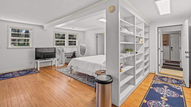 A modern bedroom with a bed, TV, and white shelving unit. - Quick Drive To Ft. Jackson, King, Full Bath, (Columbia)