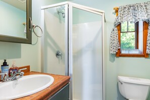 A bathroom with a glass shower enclosure, a sink with a wooden countertop, and a toilet. - Penn Cove Overlook by AvantStay | Cabin w/ Views (Oak Harbor)
