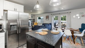A modern kitchen with a stainless steel refrigerator, granite countertops, and pendant lighting. - Twin Oaks Retreat by AvantStay | Mins to Freeland (Freeland)