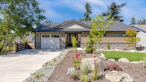 A two-story house with a garage, a front yard with a rock garden, and a small tree. - Twin Oaks Retreat by AvantStay | Mins to Freeland (Freeland)