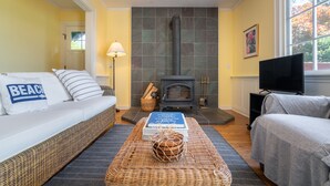 Una sala de estar acogedora con chimenea, un sofá, televisión y estantería.