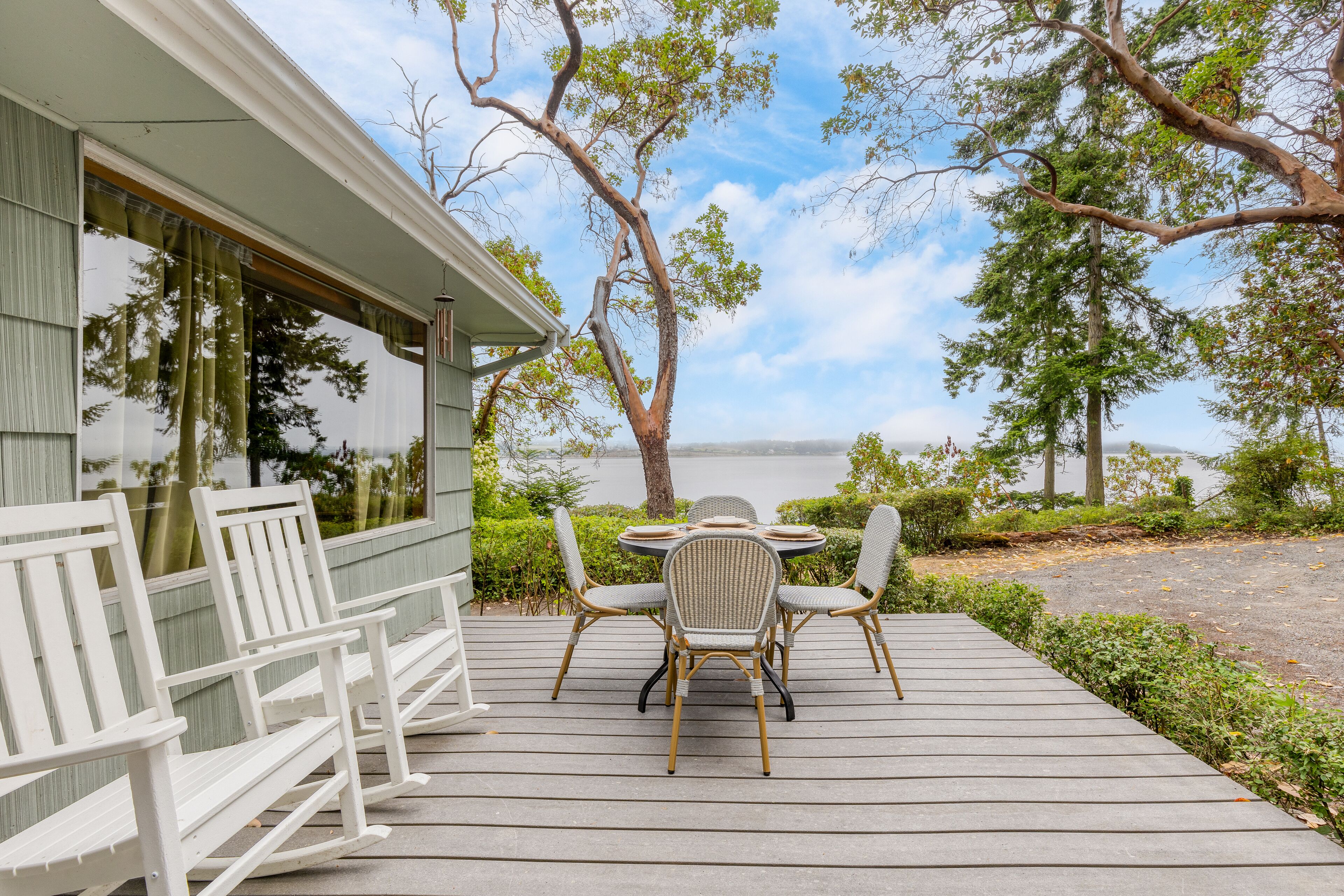 A wooden deck with outdoor seating and a view of a lake.