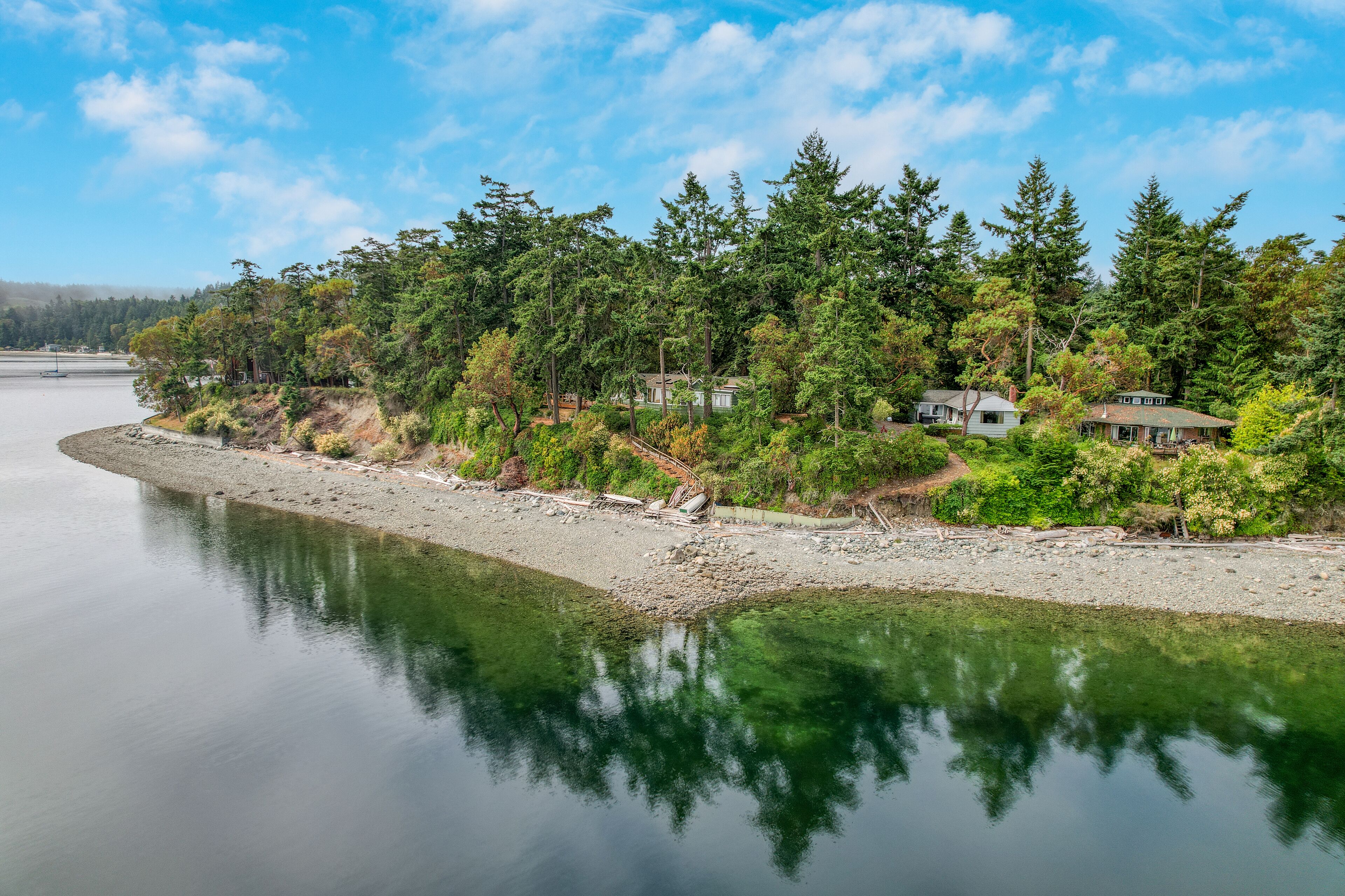 A lakeside property with a dock, surrounded by dense forest and multiple houses.