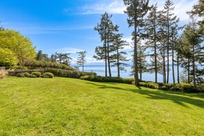 A well-maintained grassy area with a view of tall trees and a body of water in the background.