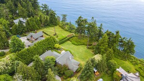 An aerial view of a residential area with houses, a well-maintained lawn, and a body of water in the background.