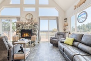 Cozy living room with a fireplace, comfortable seating area, and large windows offering a view of the outdoors.
