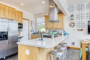 Enjoy cooking in this kitchen with a central island, stainless steel appliances, and a large range hood.