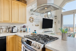 Enjoy ocean views from the kitchen window, featuring a gas range, oven, and ample kitchen appliances.