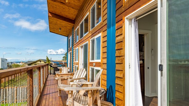A wooden deck with outdoor seating and a glass door leading to a room. - Lagoon Point Retreat • Beach Access + Fire Pit + Game Room | Chateau Coho (Greenbank)