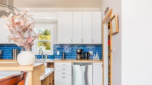 A modern kitchen with white cabinets, a blue tiled backsplash, and stainless steel appliances. - Lagoon Point Retreat • Beach Access + Fire Pit + Game Room | Chateau Coho (Greenbank)