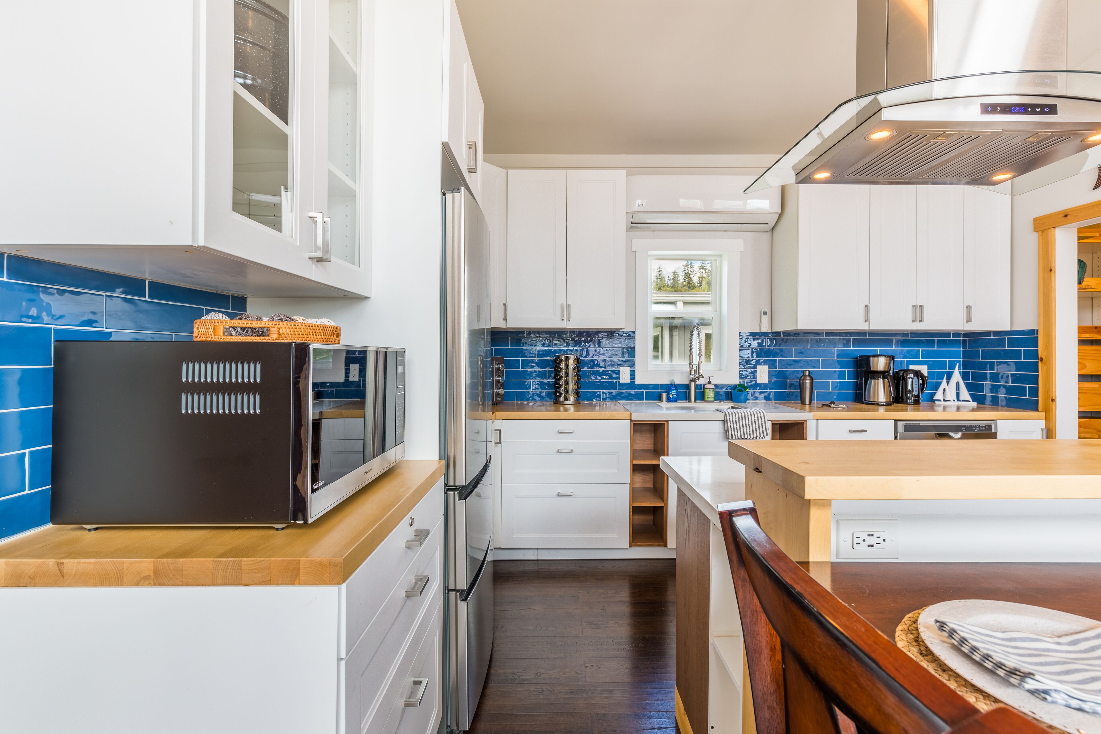Eine moderne Küche mit weißen Schränken, einem schwarzen Kühlschrank und einer blauen Fliesenrückwand.