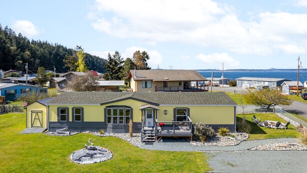 Une maison de plain-pied dotée d’un porche à l’avant, d’une petite terrasse et d’un jardin aménagé avec un élément décoratif circulaire en gravier.