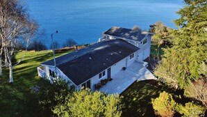 A two-story house with a large deck overlooking a body of water. - Marine View Bluff by AvantStay | Waterfront Views (Greenbank)