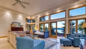 A spacious living room with a large window, a ceiling fan, and a view of the outdoors.