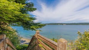 A wooden staircase leading to a beach with a clear view of the water and distant land.