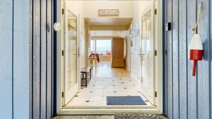 L’entrée d’un hôtel, avec une pancarte indiquant « BIENVENUE », un banc et une vue sur l’intérieur.